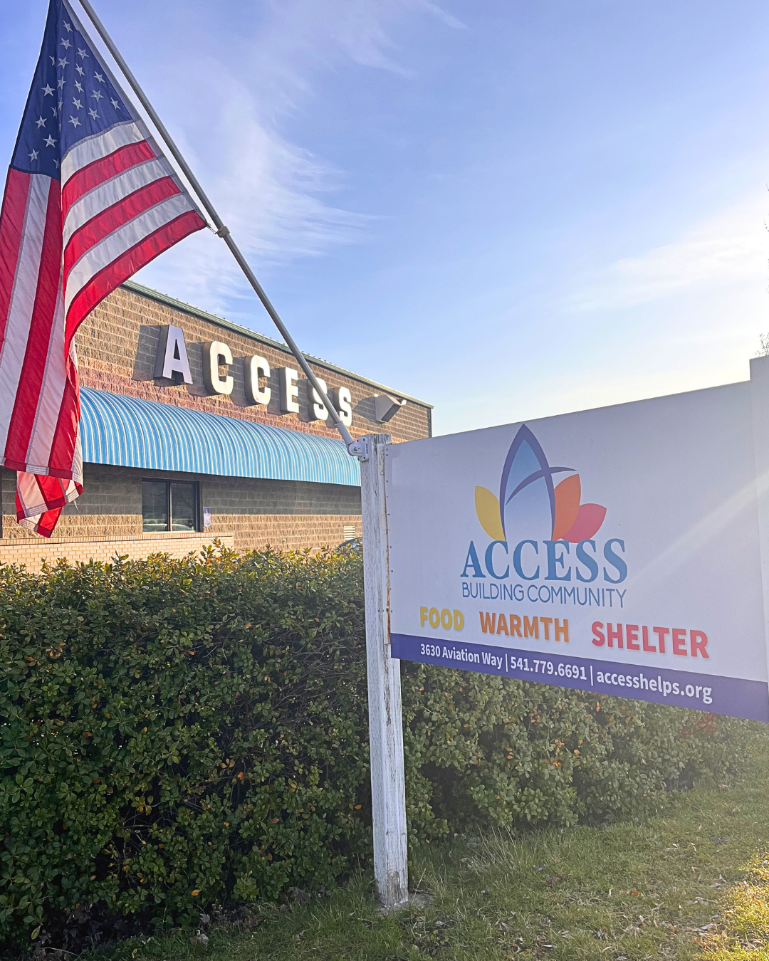 Photo of the ACCESS main building with an ACCESS sign and an American Flag